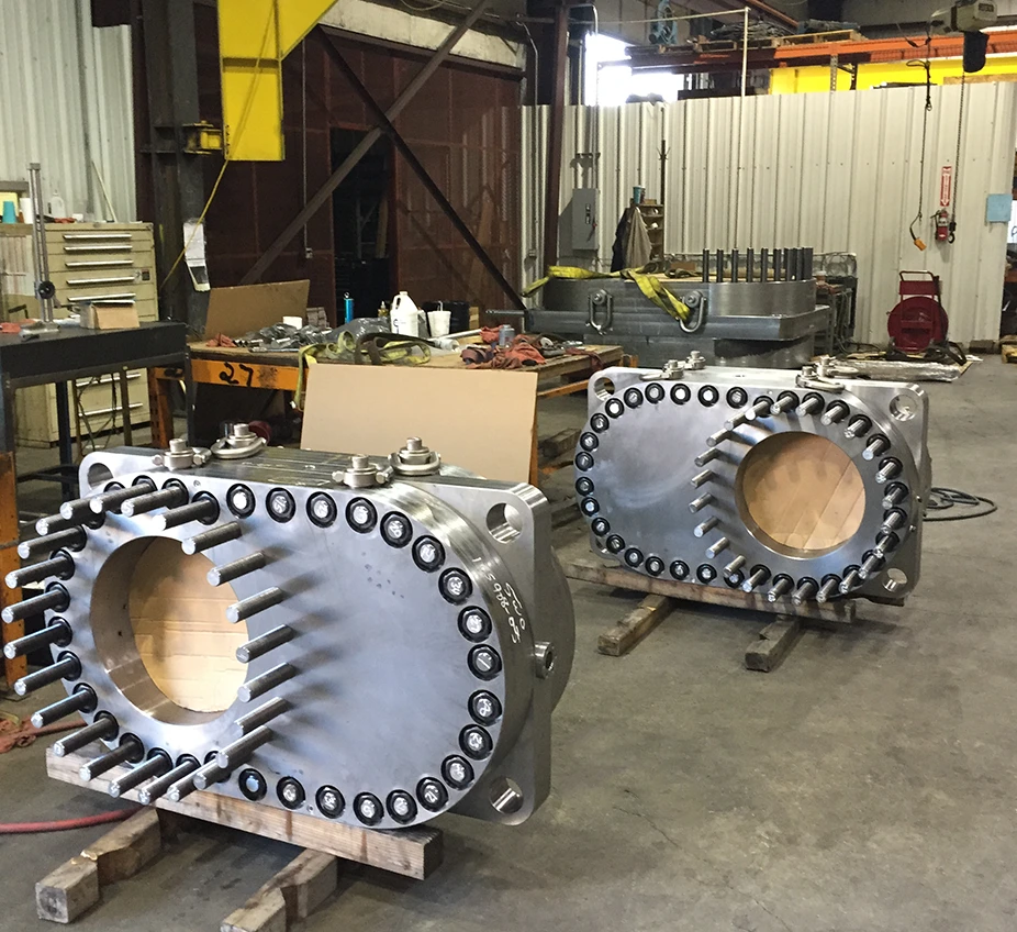 two large components sitting on shop floor with overhead jib crane in background