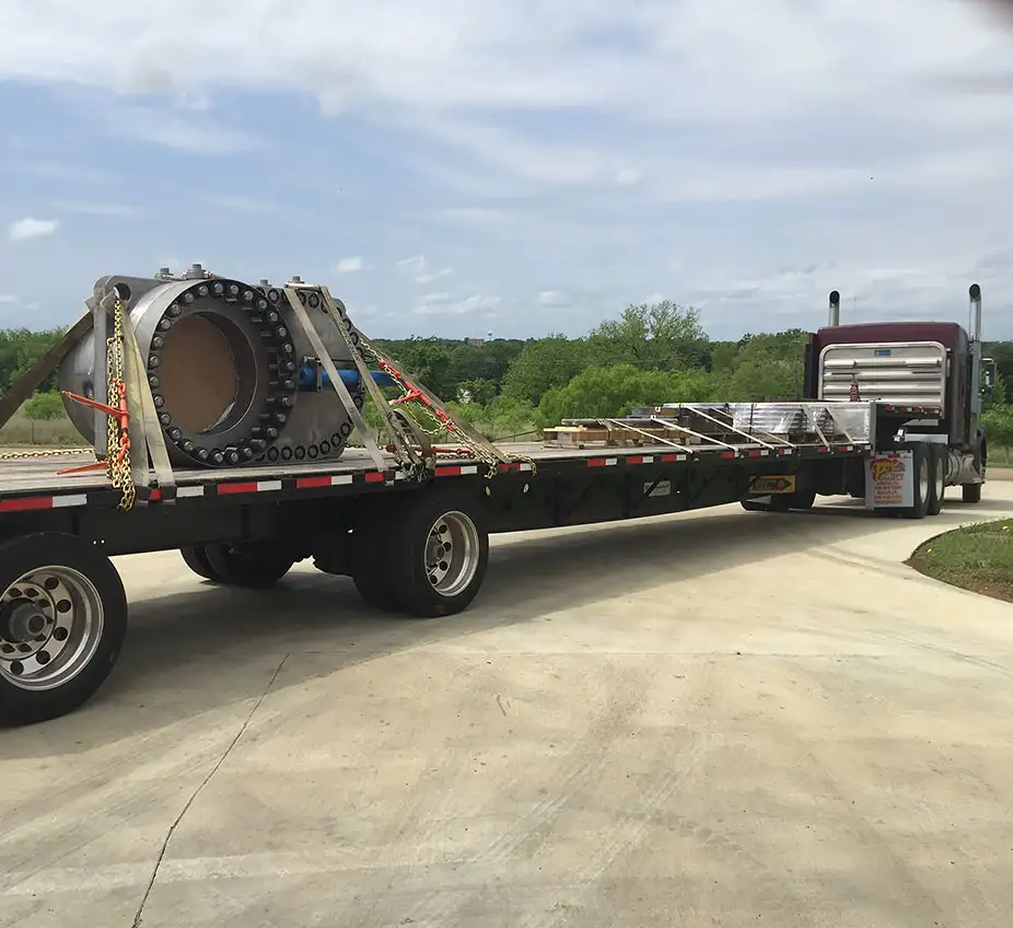 machined part strapped onto bed of lowboy trailer in process of being delivered